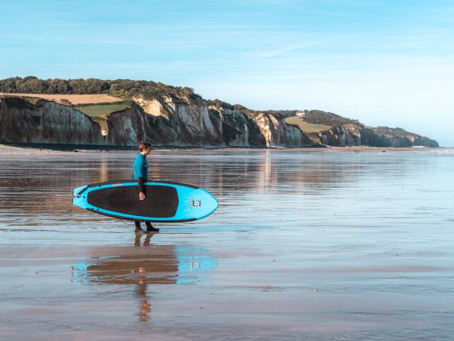 Jeune surfeur face aux falaises