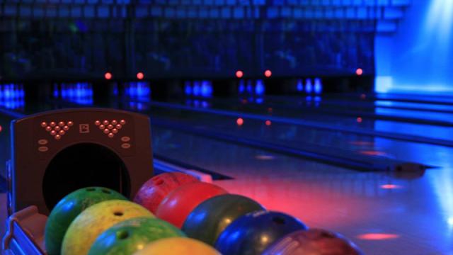 Boules de bowling de toutes les couleurs devant la piste plongée dans la pénombre