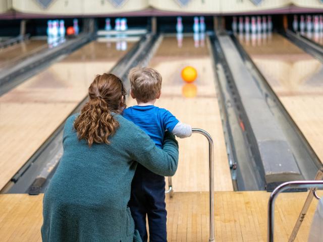 Une femme et un enfant viennent de lancer une boule sur une piste de bowling