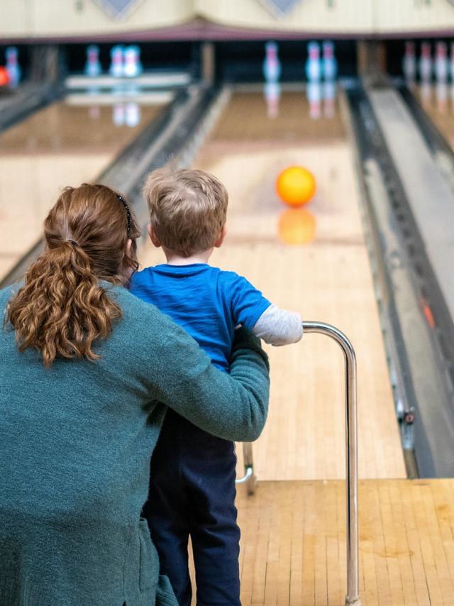 Une femme et un enfant viennent de lancer une boule sur une piste de bowling