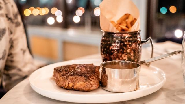 Assiette avec une viande rouge, des frites et une sauce.