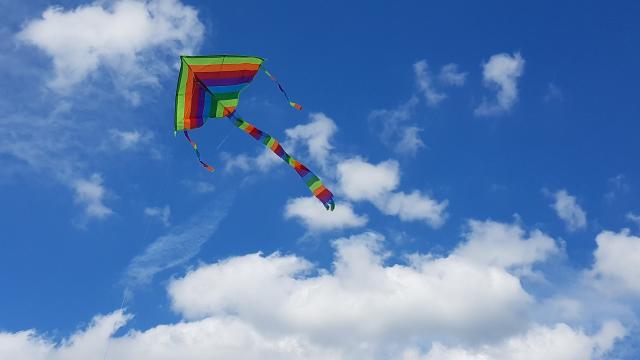 Cerf-volant triangulaire multicolore volant dans un ciel bleu