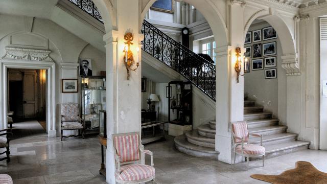 Hall d'entrée du Château de Miromesnil, arches blanches, escalier, meubles d'époque