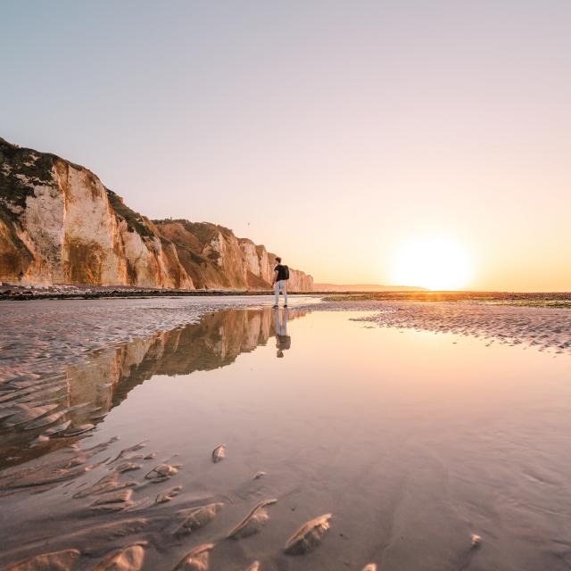 Jeune homme regardant les falaises depuis la plage de Dieppe à marée basse durant le coucher de soleil