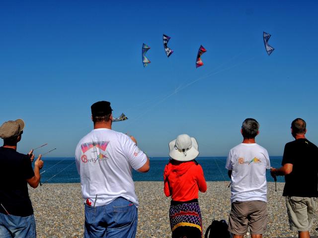 5 personnes font voler des cerfs-volants au-dessus des galets de la plage de Dieppe