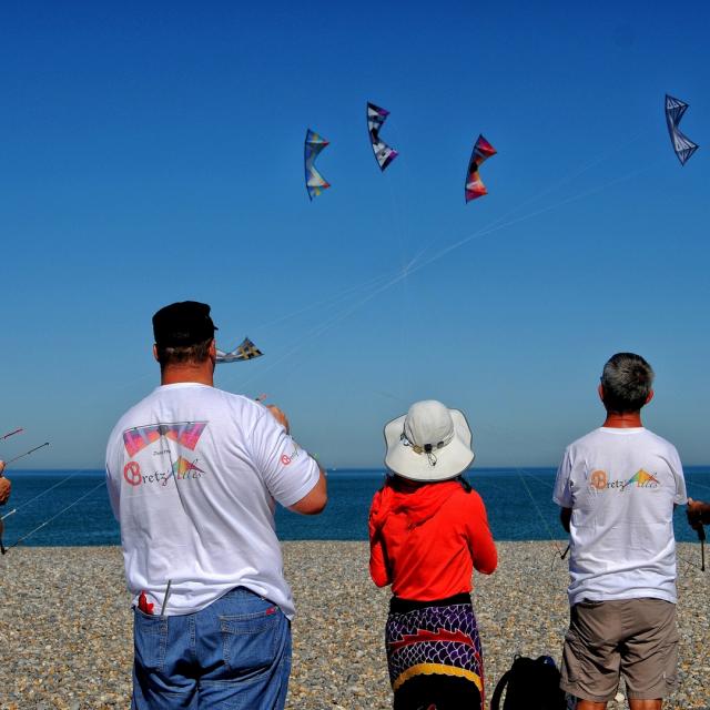 5 personnes font voler des cerfs-volants au-dessus des galets de la plage de Dieppe