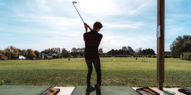 Jeune homme de dos en train de jouer au golf