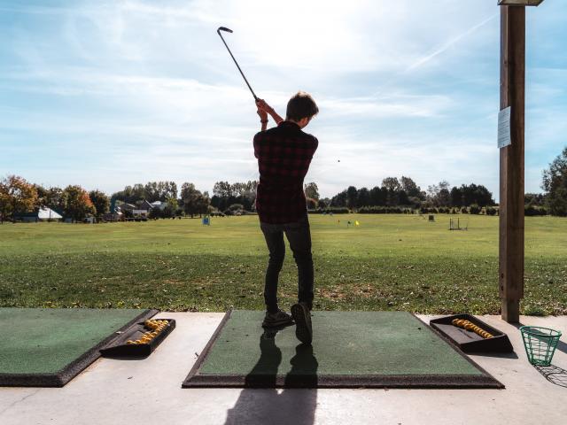 Jeune homme de dos en train de jouer au golf