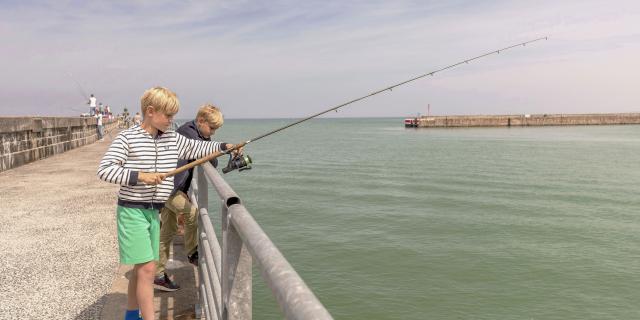 Deux jeunes garçons pêchant avec une canne sur la jetée