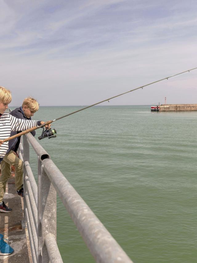 Deux jeunes garçons pêchant avec une canne sur la jetée