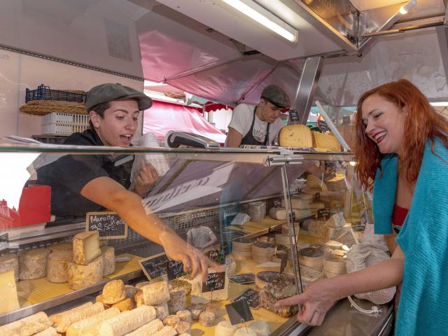 Les producteurs de fromage vendent leurs produits à une dame sur le marché de Dieppe