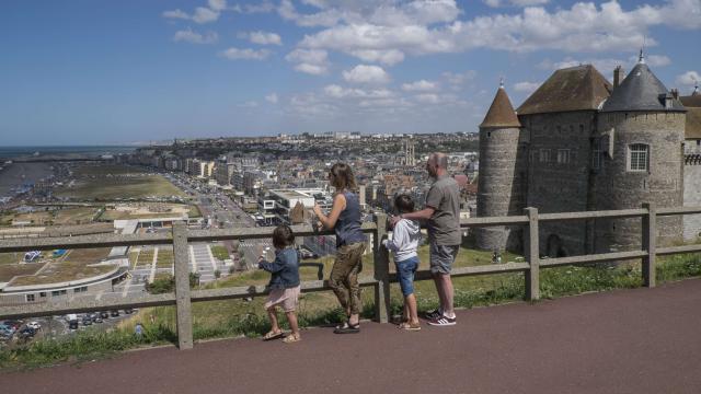 Un couple, un petit garçon et une petite fille de dos admirant le panorama sur la ville et la plage depuis l'esplanade du Château de Dieppe