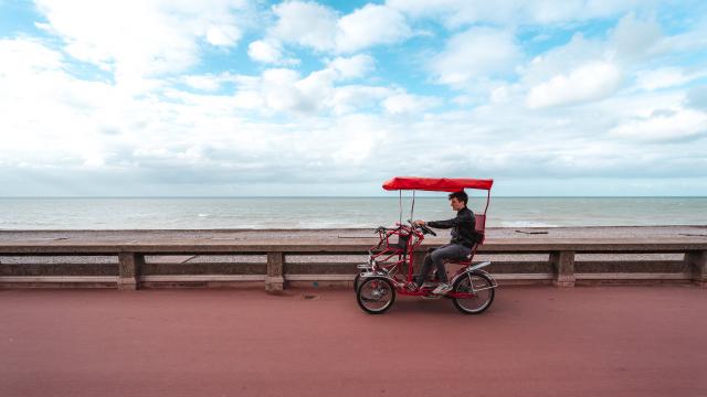 Jeune homme pédalant sur une rosalie sur le front de mer de Dieppe