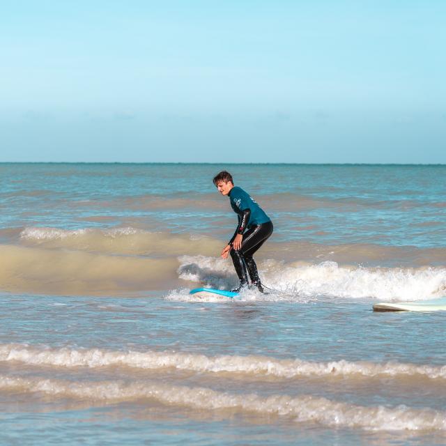 Deux surfeurs dans l'eau prenant les vagues à la plage de Pourville-sur-Mer