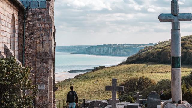 Jeune homme admirant le point de vue donnant sur la côte avec les falaises depuis le cimetière marin de l'église St Valery.