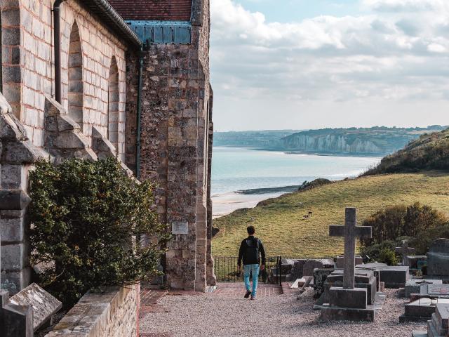 Jeune homme admirant le point de vue donnant sur la côte avec les falaises depuis le cimetière marin de l'église St Valery.