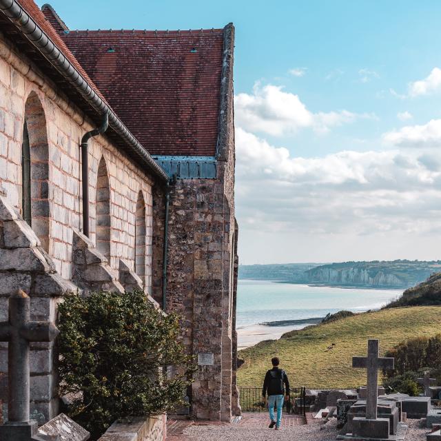 Jeune homme admirant le point de vue donnant sur la côte avec les falaises depuis le cimetière marin de l'église St Valery.