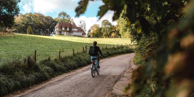 Jeune homme à vélo devant un manoir dans le village de Varengeville-Sur-Mer.