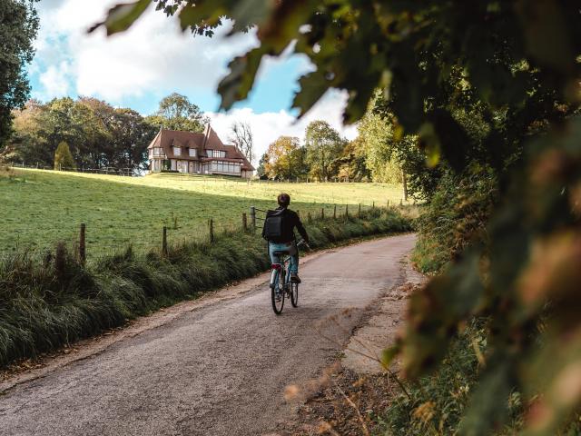 Jeune homme à vélo devant un manoir dans le village de Varengeville-Sur-Mer.