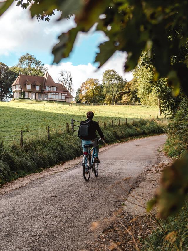 Jeune homme à vélo devant un manoir dans le village de Varengeville-Sur-Mer.