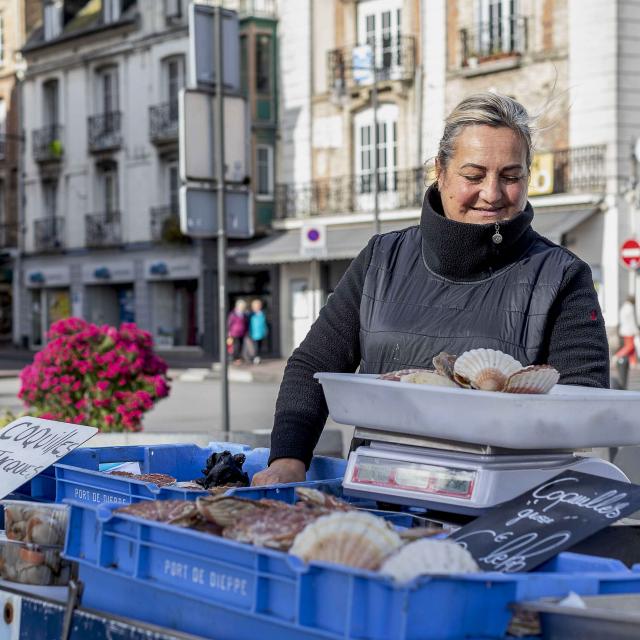 Une femme de pêcheurs vend des coquilles Saint-Jacques sur le marché aux poissons de Dieppe.