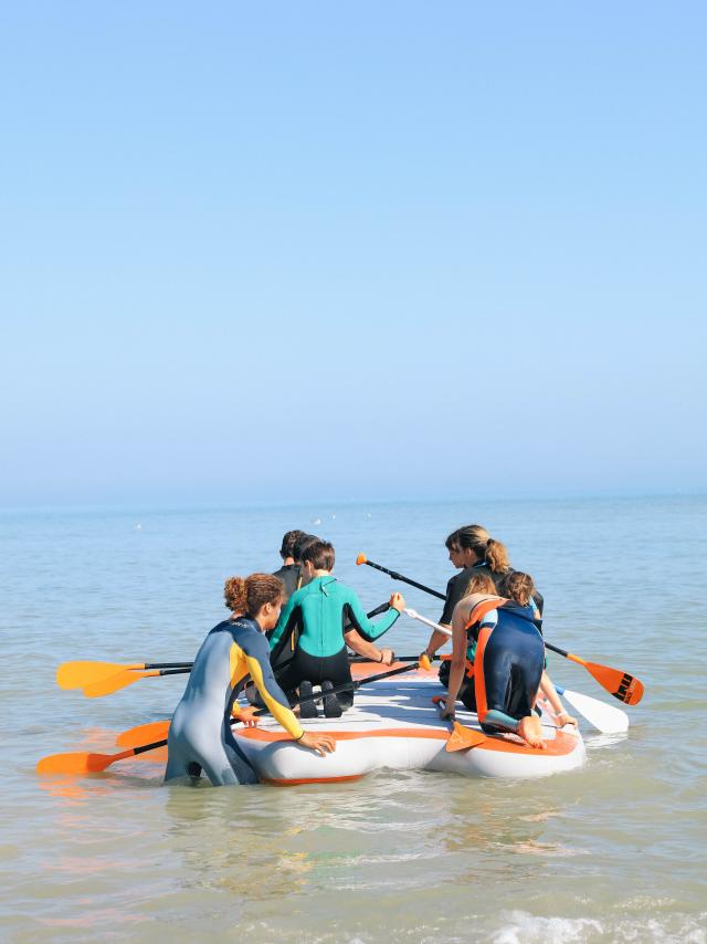 Un groupe de jeunes gens faisant du paddle géant en mer