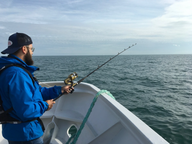 Jeune en homme pêchant avec une canne depuis un bateau