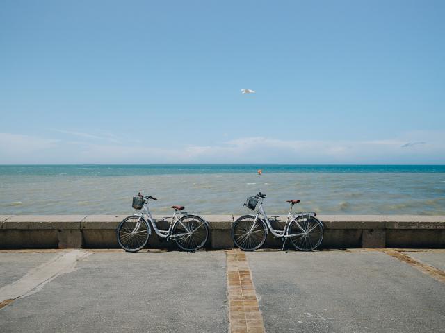 2 vélos poser sur le parapet du front de mer de Dieppe devant une mer et un ciel bleus