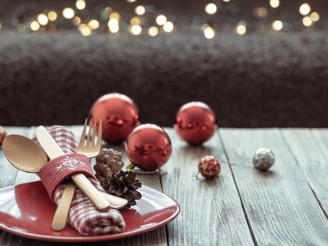 Close up of Christmas festive table setting on blurred dark background with bokeh, copy space.