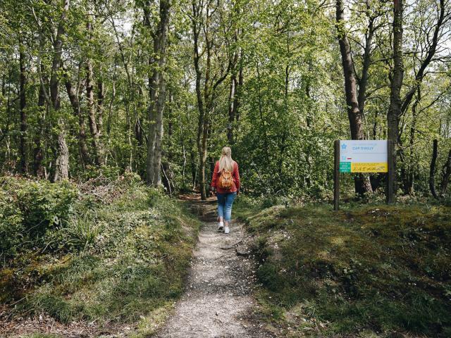 Jeune femme sur un chemin de randonnée à la végétation verdoyante