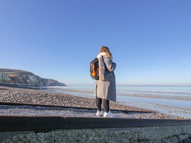 Jeune femme avec un sac à dos regardant la mer sur la plage de Pourville à marée basse