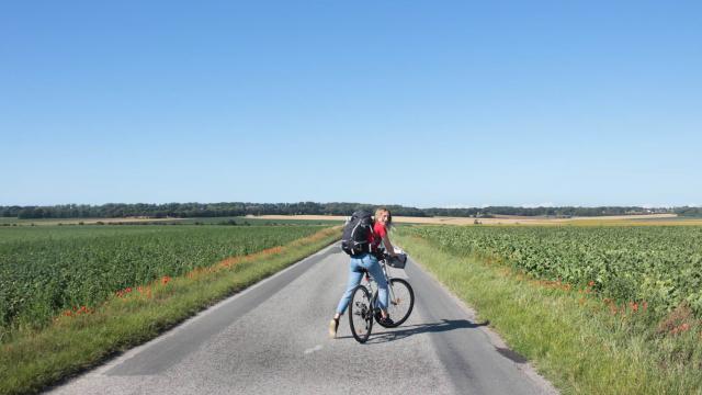 Jeune femme à vélo sur une route à travers champs