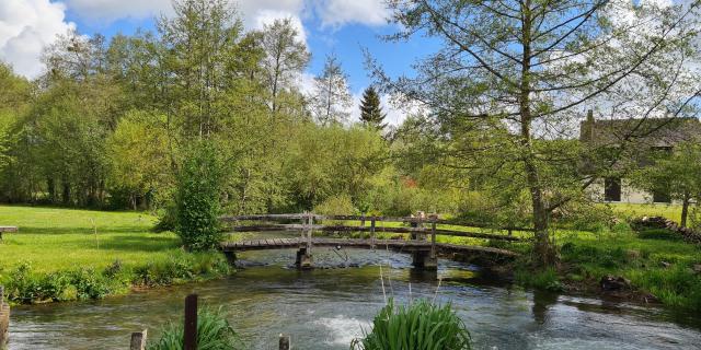 Paysage verdoyant avec un pont qui enjambe une rivière et une maison à droite