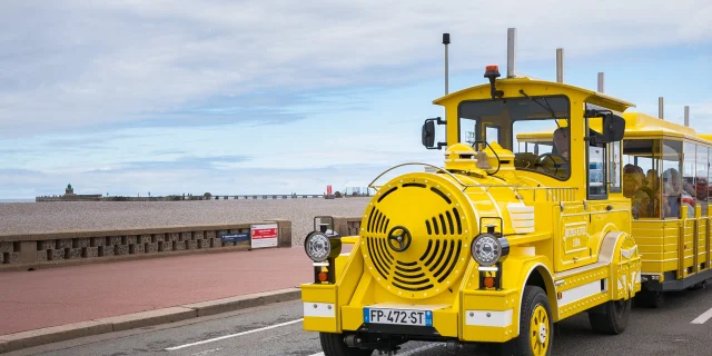 Le petit train touristique jaune rempli de visiteurs devant le front de mer de Dieppe