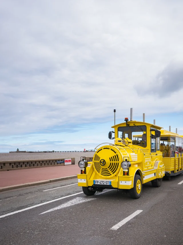 Le petit train touristique jaune rempli de visiteurs devant le front de mer de Dieppe