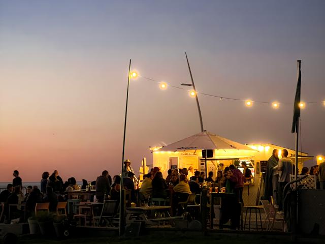 Terrasse pleine de monde d'un bar de plage au coucher du soleil