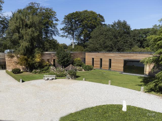 Cour intérieure du musée entourée de bâtiment de plain-pied en bois, d'arbres et de végétation