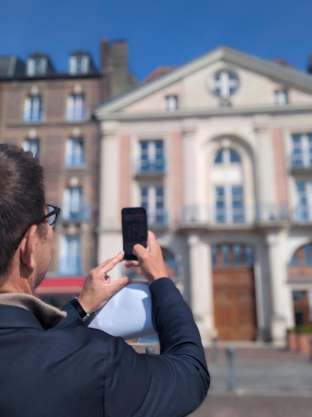 Un homme dirige son smartphone vers l'hôtel des oratoriens sur le quai Henri 4 à Dieppe