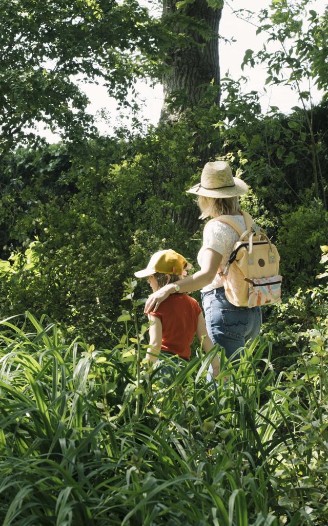 Une maman et sa fille se baladent dans un jardin arboré