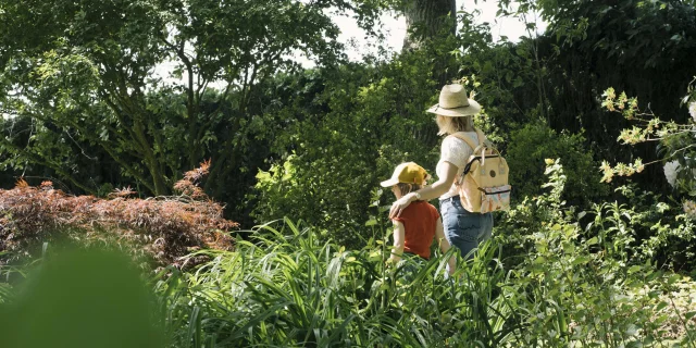 Une maman et sa fille se baladent dans un jardin arboré