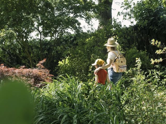 Une maman et sa fille se baladent dans un jardin arboré