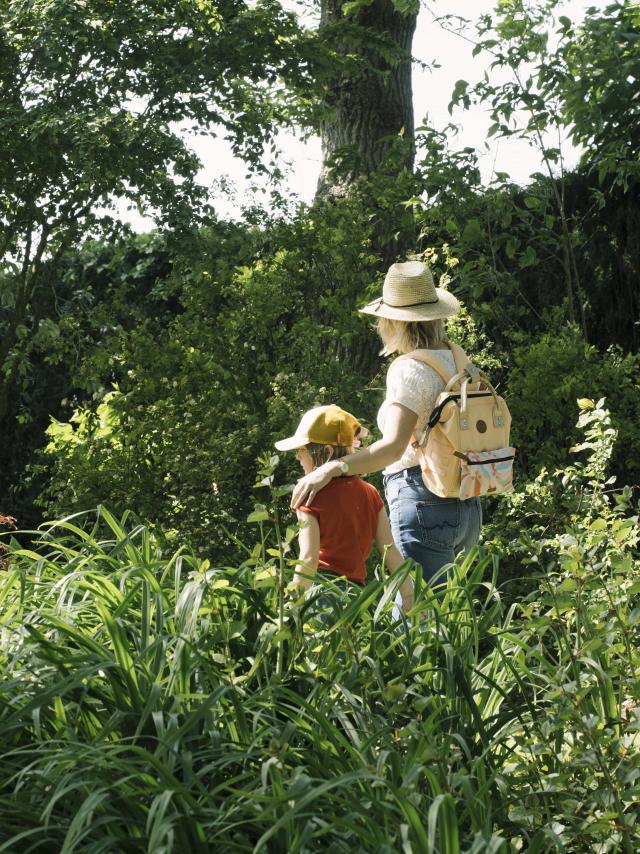 Une maman et sa fille se baladent dans un jardin arboré