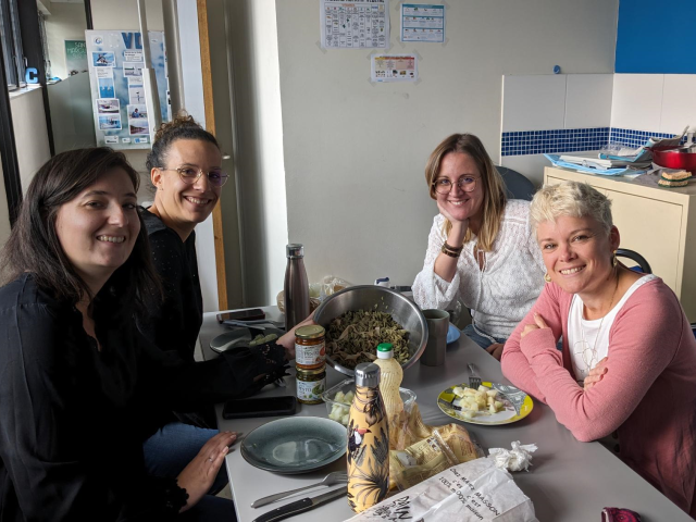 4 jeunes femmes sourient face à l'objectif devant un déjeuner de travail végétarien