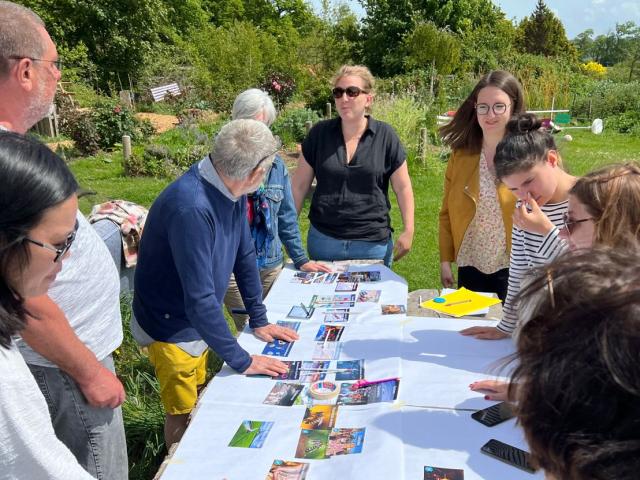 Un groupe d'une dizaine de personnes rassemblés autour d'une table devant le jeu éducatif 