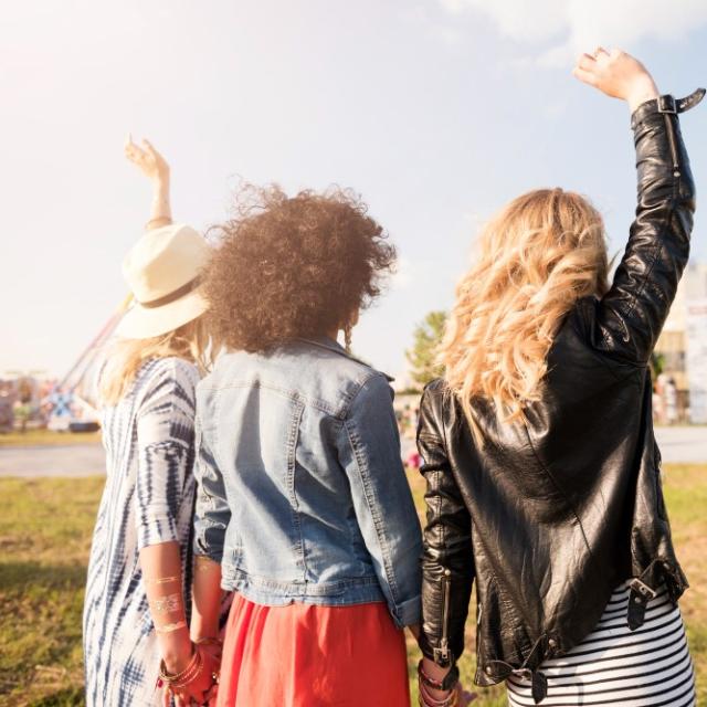 3 jeunes femmes en tenue d'été dansant devant un concert sous chapiteau