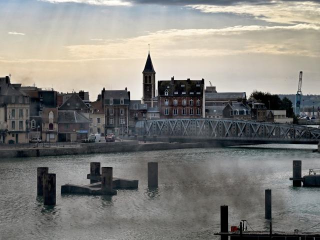 Le pont Colbert au-dessus de l'eau et le quartier du Pollet en arrière-plan, avec le clocher de l'église Notre-Dame des Grèves ; dans une lumière déclinante de fin de journée