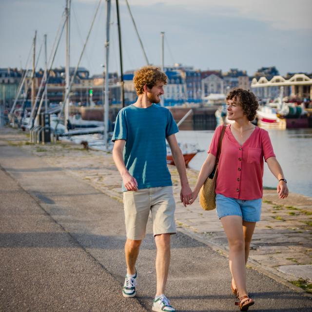 Un homme et une femme se tenant par la main et se regardant amoureusement se balade le long d'un quai du port de Dieppe