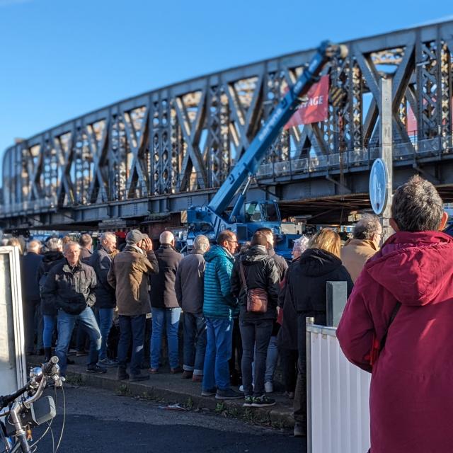 Un public nombreux assiste au transport du pont Colbert, un grand pont en fer, le long du port