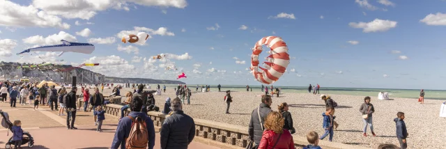 Une foule qui se promène sur le front de mer avec des cerfs-volants au-dessus d'eux