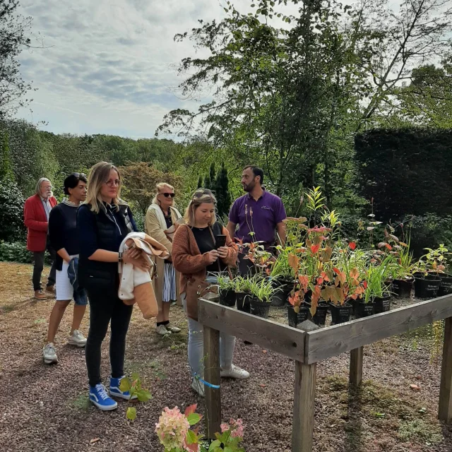 Jeune femme prenant en photo des pots de fleurs dans un groupe de visiteur d'un jardin